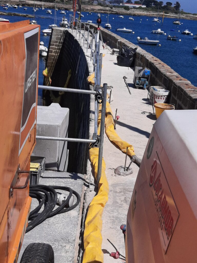 Photo des machines et tuyaux installés sur la digue de Lomener dans le cadre des travaux de confortement